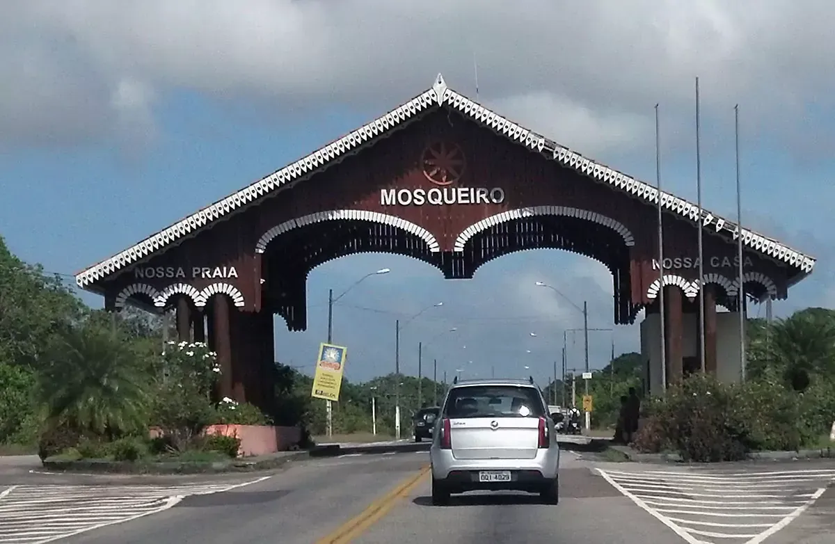 Um carro está passando por baixo de um arco de madeira que diz nossa pena -HOTEL-FAZENDA-PARAISO