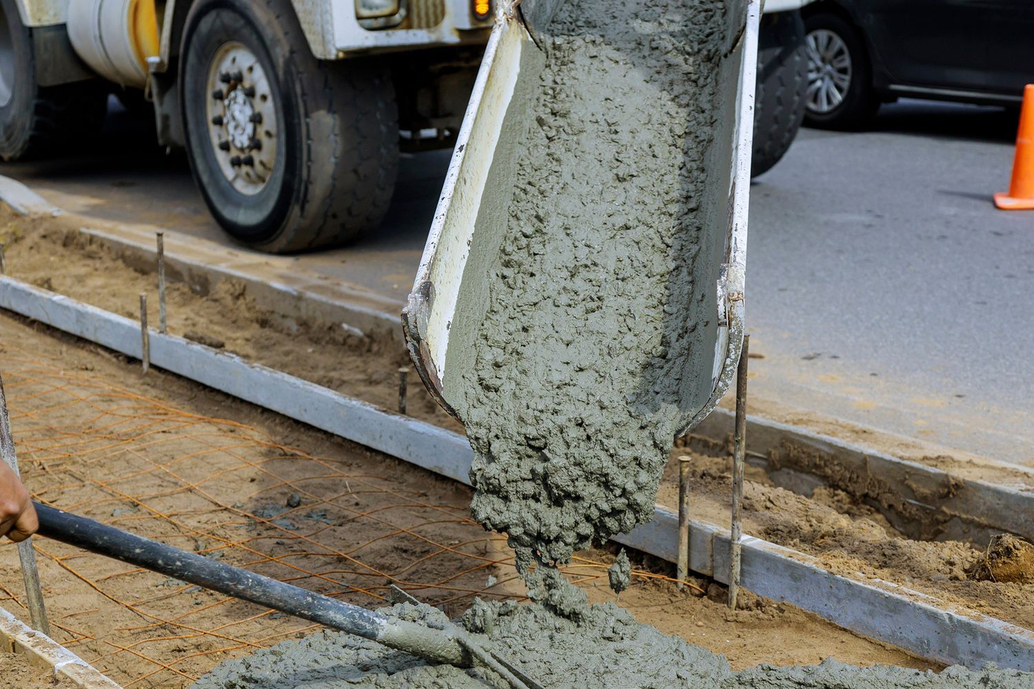 Concrete being poured from a truck into a form for a sidewalk.