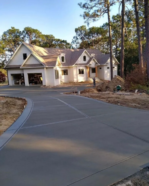 Brick house with concrete driveway bordered by red bricks and green grass.