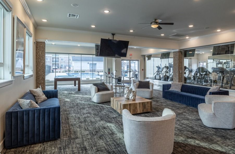 Centerton clubhouse with large couches, arm chairs, a coffee table, and giant windows.