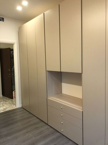 corridoio con parquet in legno, mobili color bianco e sulla destra uno scorrimano in metallo a Segrate, MI