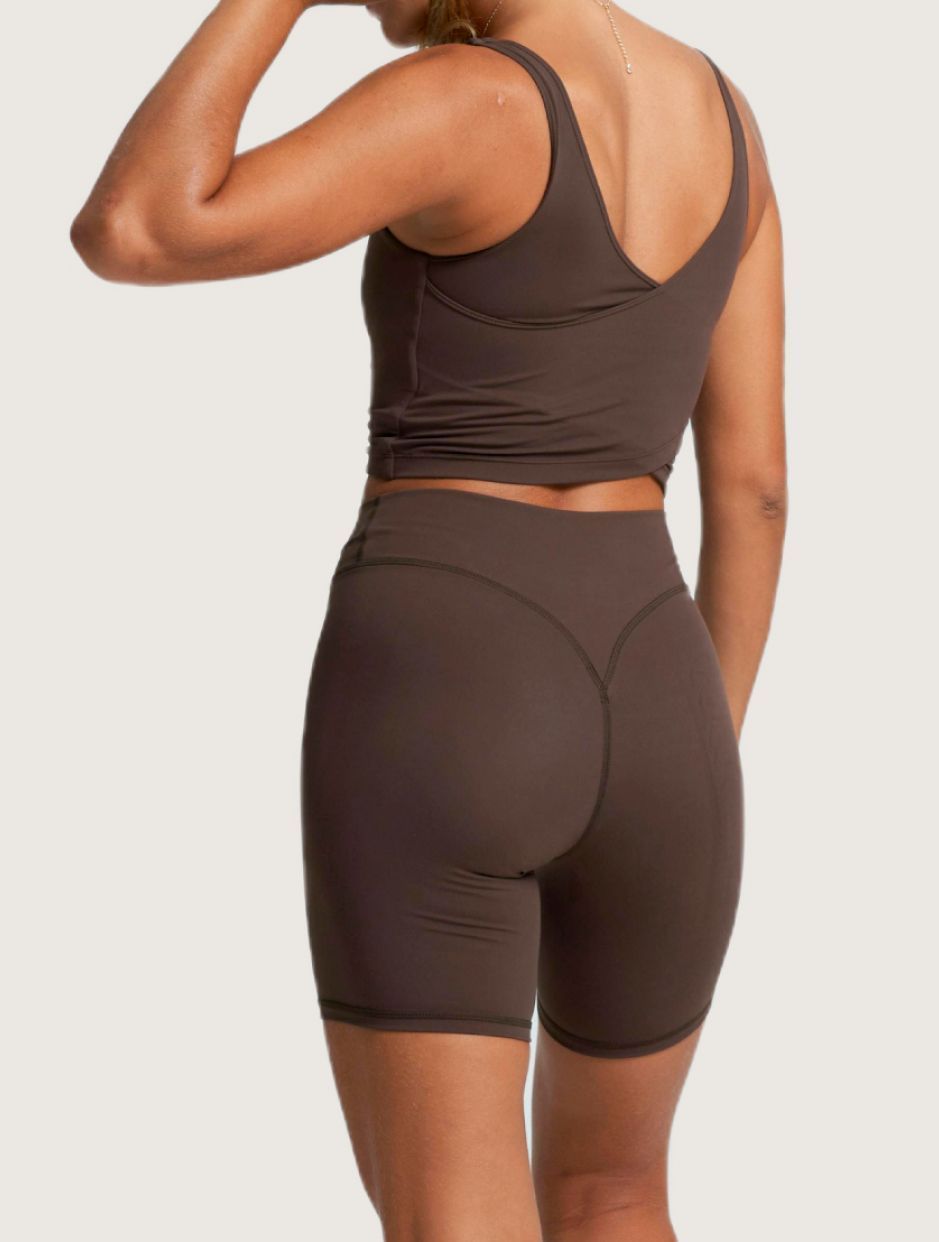 A person seen from behind, wearing a brown athletic tank top cycling.