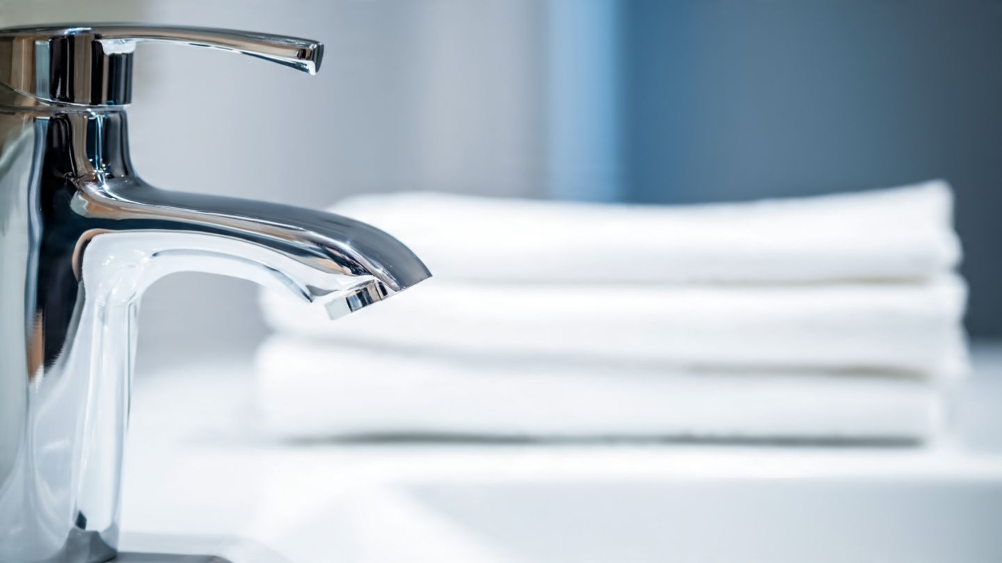 Chrome faucet beside neatly folded white towels in a bright bathroom