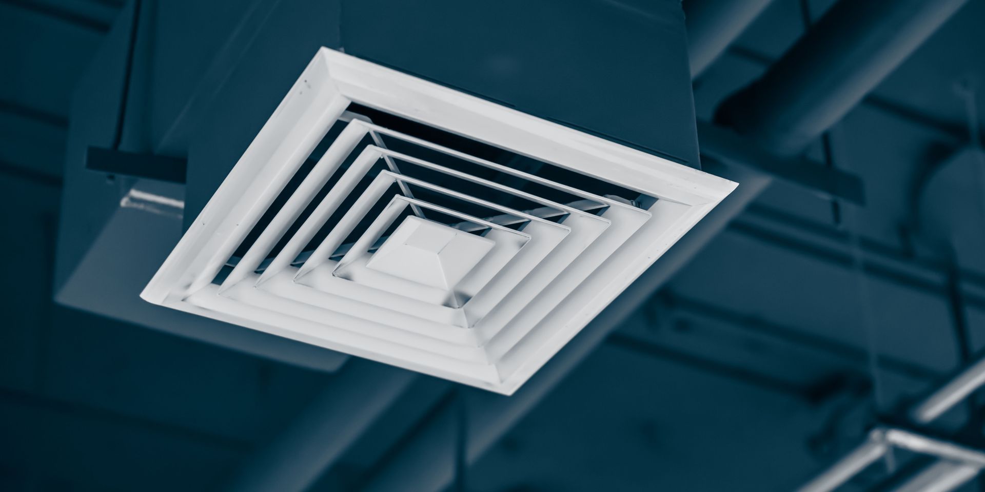 A square air vent is hanging from the ceiling of a building.