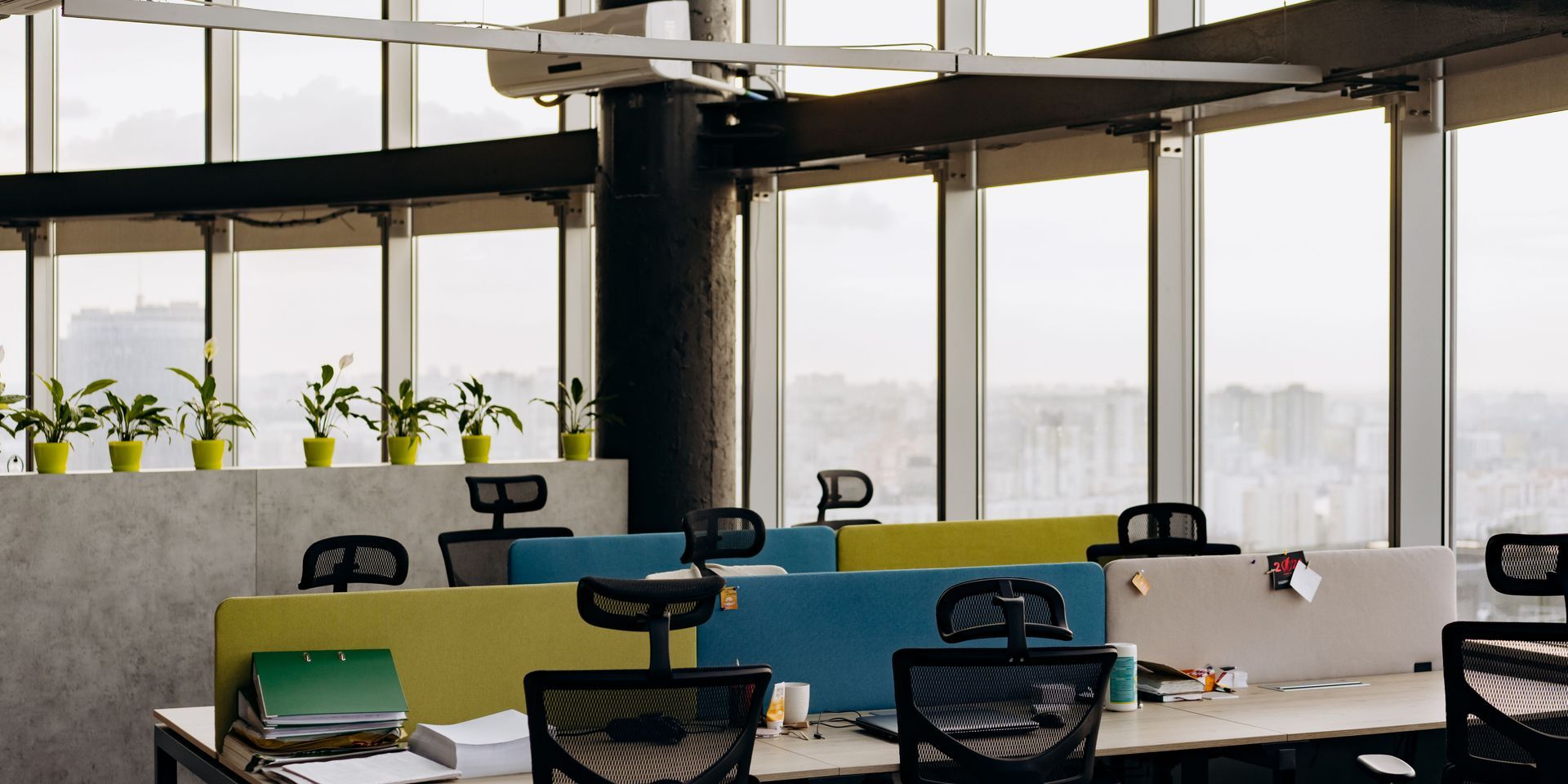 A row of desks and chairs in an office with lots of windows.