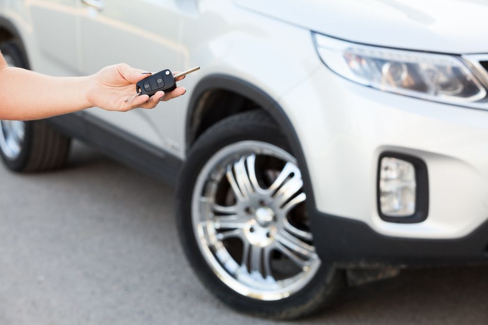A Person is Holding a Car Key in Front of a White Car — Duffys Car Rentals in Malanda, QLD