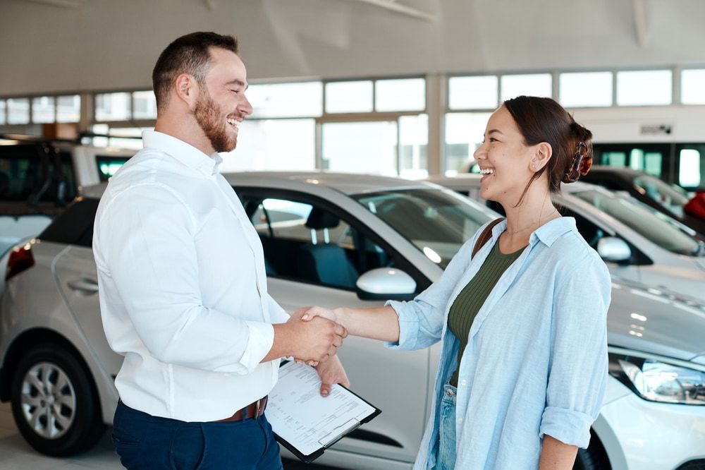 A Man and a Woman Are Shaking Hands in a Car Showroom — Duffys Car Rentals in Mareeba, QLD