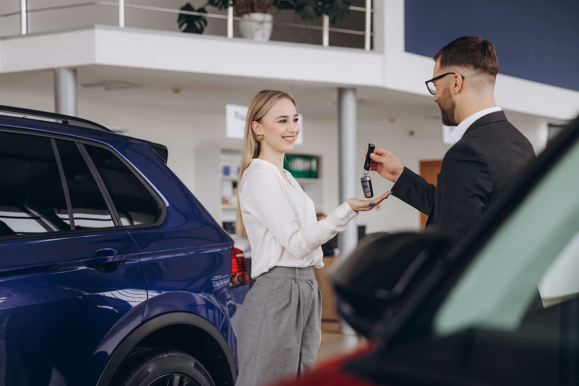 A Man is Giving a Woman a Car Key in a Car Showroom ā Duffys Car Rentals in Ravenshoe, QLD
