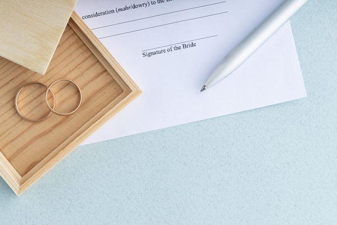 A pair of wedding rings sitting on top of a piece of paper next to a pen.