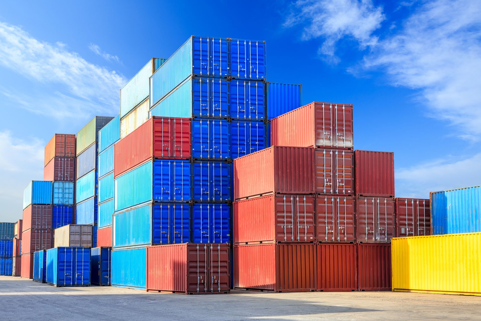 Stacked colorful shipping containers against a bright blue sky.