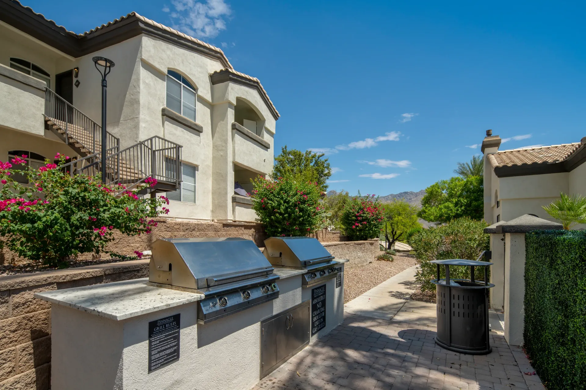 Outdoor grilling area with two built-in stainless steel grills and a trash receptacle at Pinnacle Heights in Tucson, AZ.
