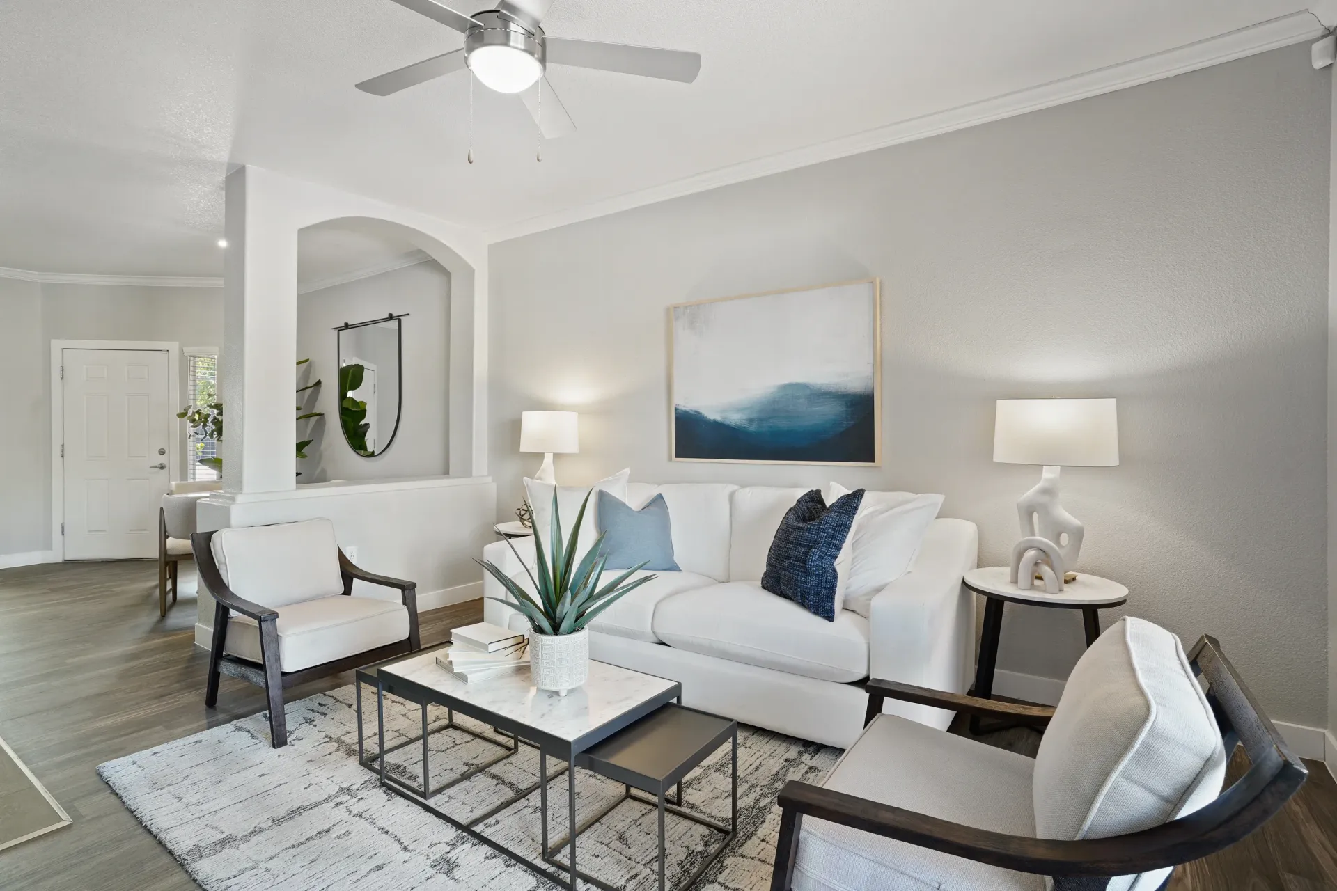 Modern living room with a white couch, accent chairs, and abstract art.
