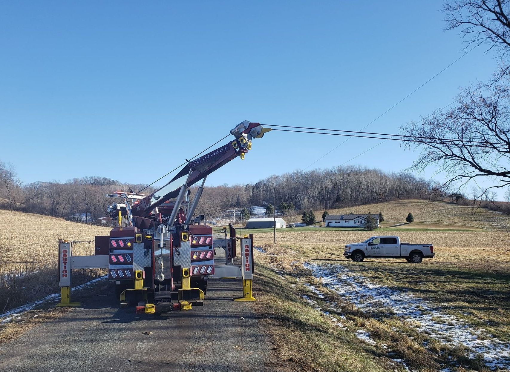 A white truck is parked on the side of the road next to a crane.