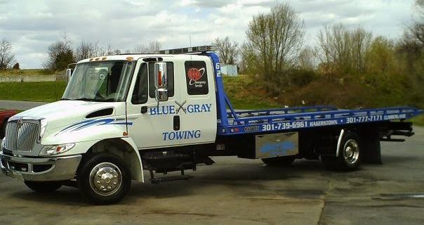 A blue gray towing truck is parked in a parking lot