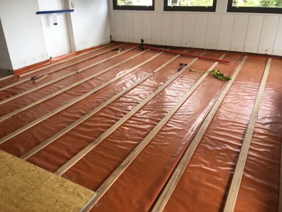 A room with wooden beams and orange plastic on the floor.