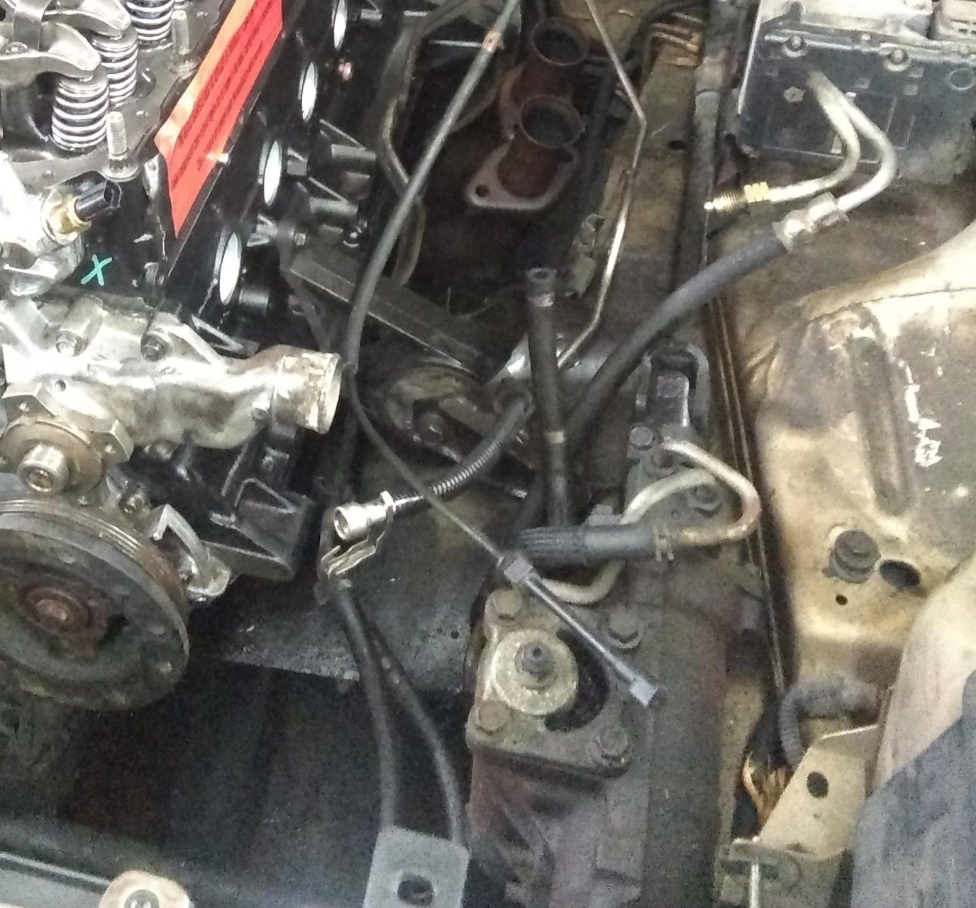 Engine bay with engine components, hoses, and tubes; partly disassembled car | Lowry Auto Service