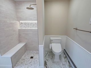 Accessible bathroom with walk-in shower, toilet, and marble tile flooring.