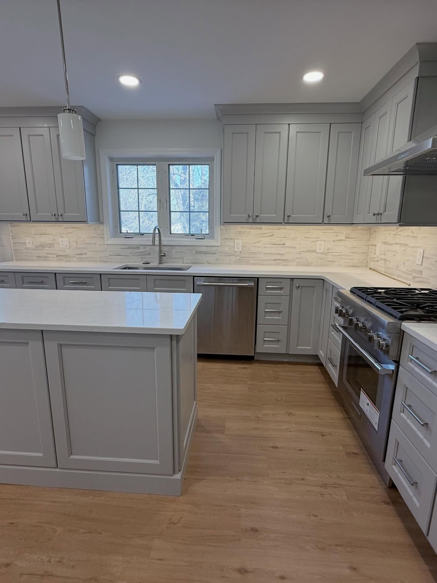 Bright modern kitchen with gray cabinets, white countertops, stainless appliances, and a large island