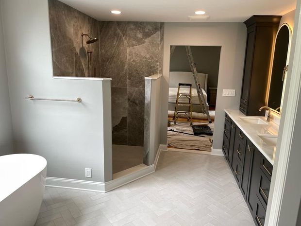 Bathroom under renovation with tiled shower, bathtub, vanity, and construction ladder in doorway