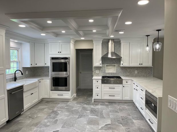 Bright modern white kitchen with gray countertops, stainless appliances, island, and pendant lights