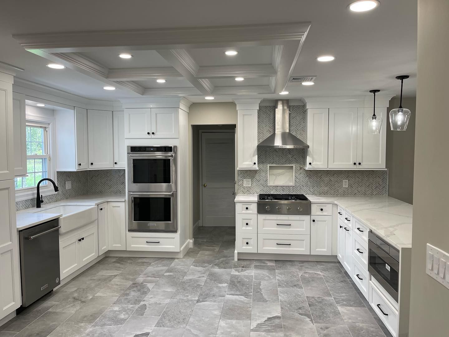 Bright modern white kitchen with gray countertops, stainless appliances, island, and recessed lighting