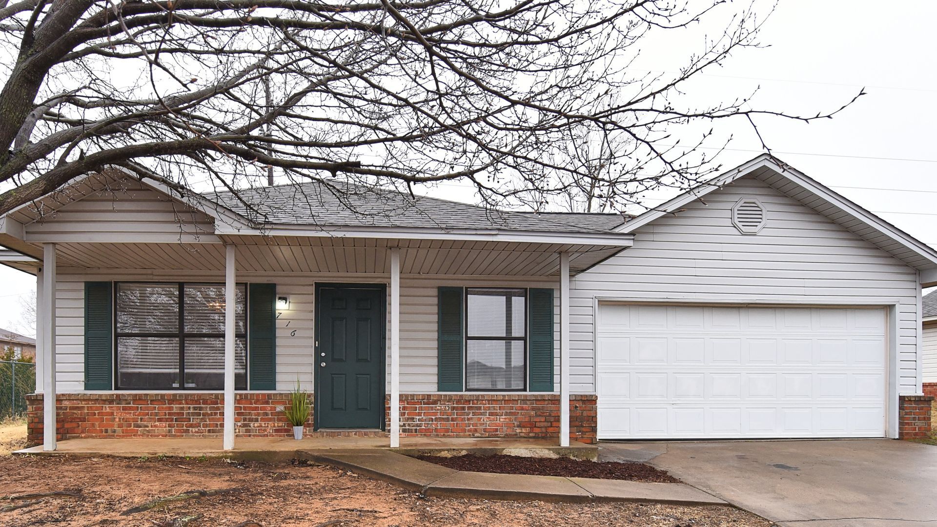 Single-story house with brick accents, green front door, and attached two-car garage.