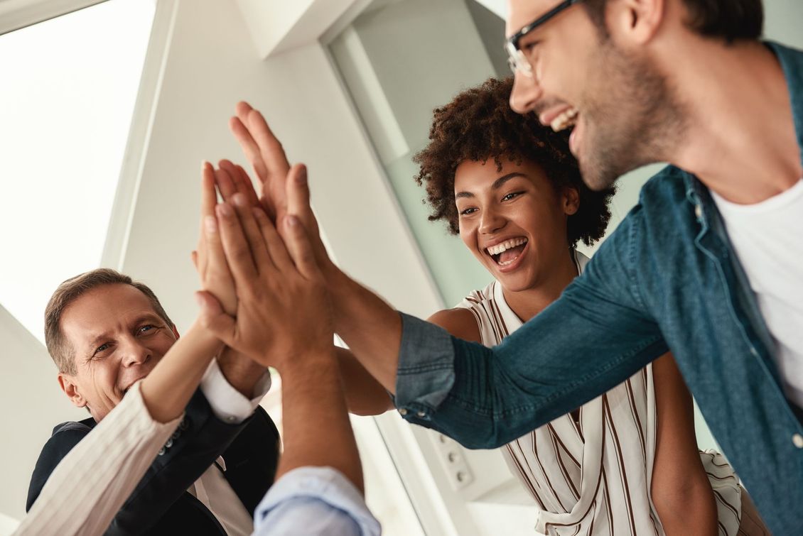 Colleagues smiling and high-fiving in a bright office setting