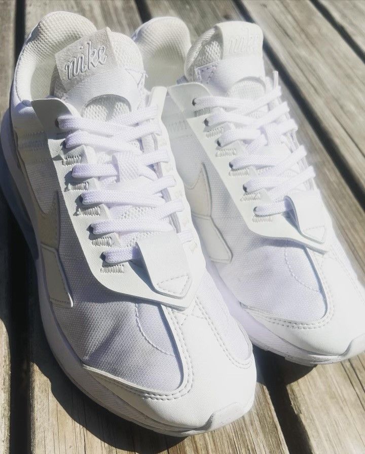 A pair of white nike shoes are sitting on a wooden table