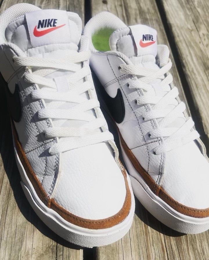 A pair of white nike sneakers are sitting on a wooden surface