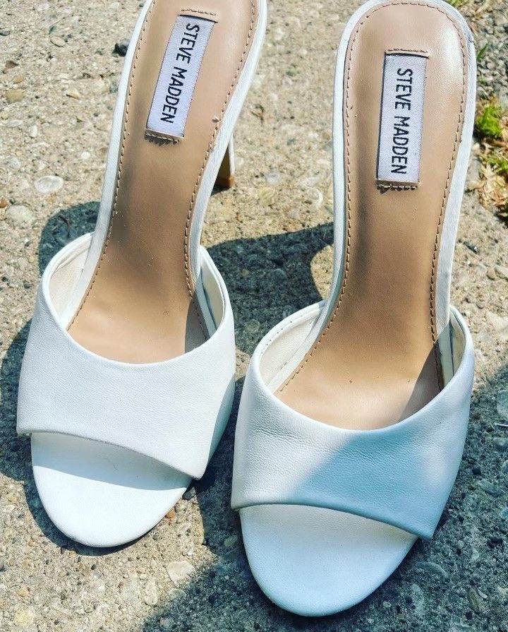 A pair of white steve madden sandals on the ground