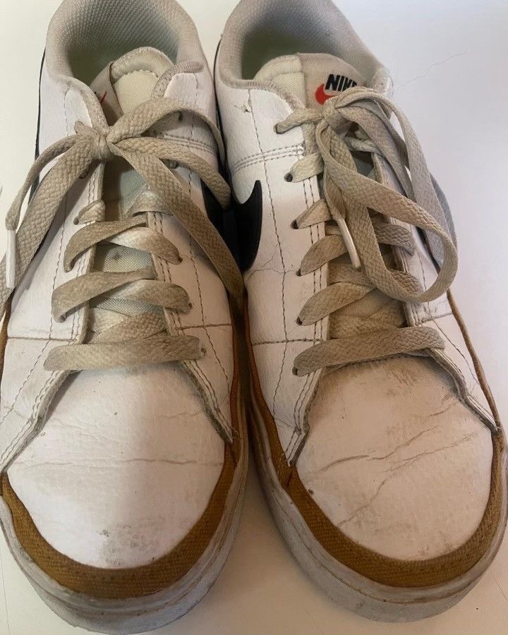A pair of white nike sneakers with brown laces