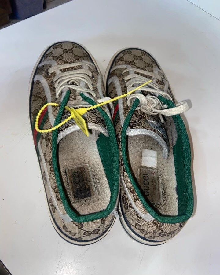 A pair of gucci sneakers are sitting on a white table.