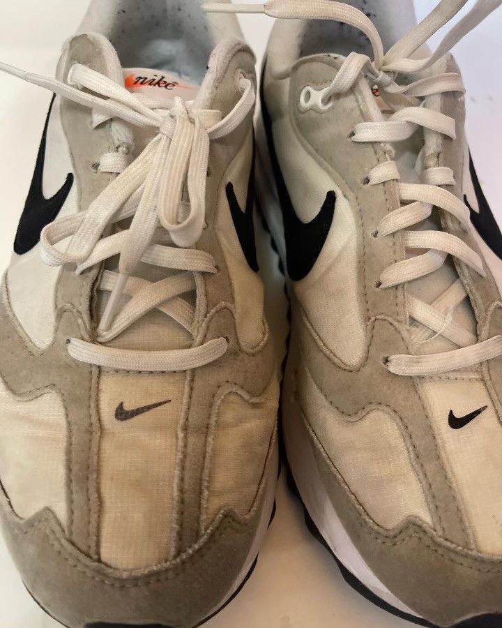 A pair of white nike shoes with black swooshes