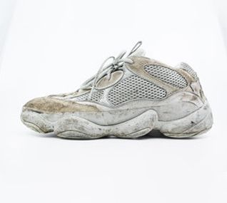 A pair of dirty white sneakers on a white background.