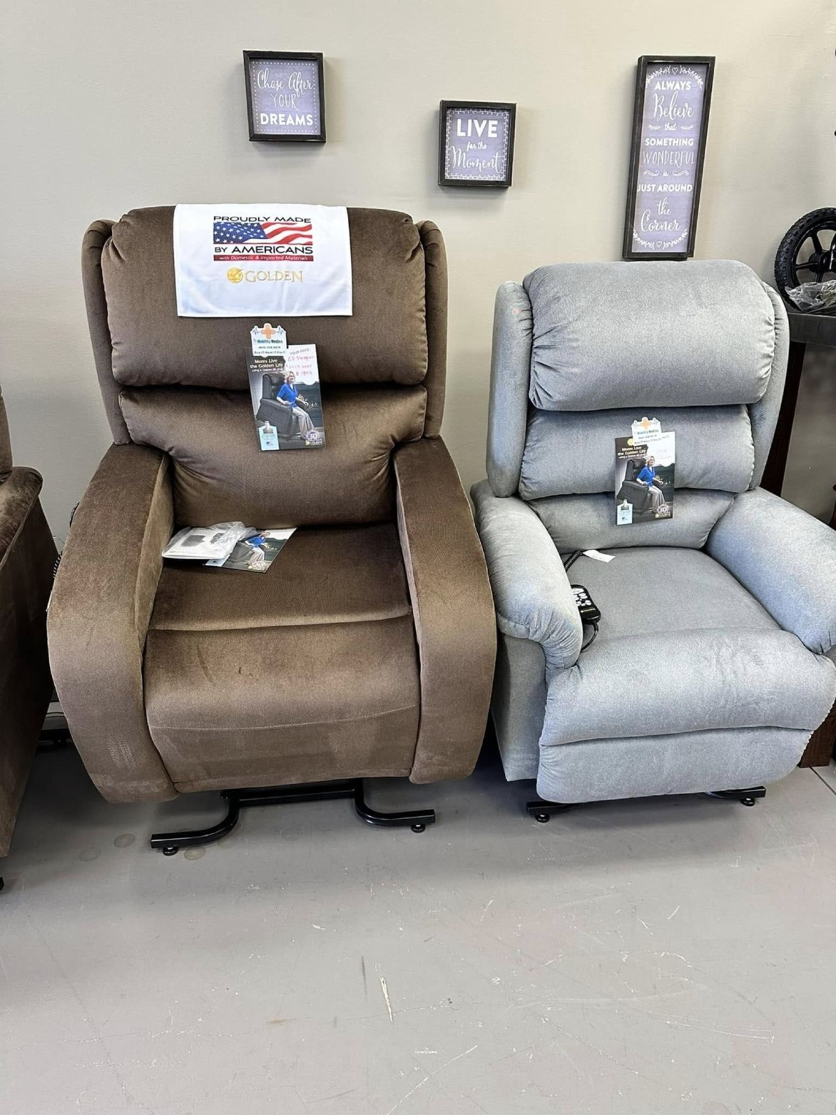 Brown and gray recliner chairs displayed in a showroom with framed signs on the wall