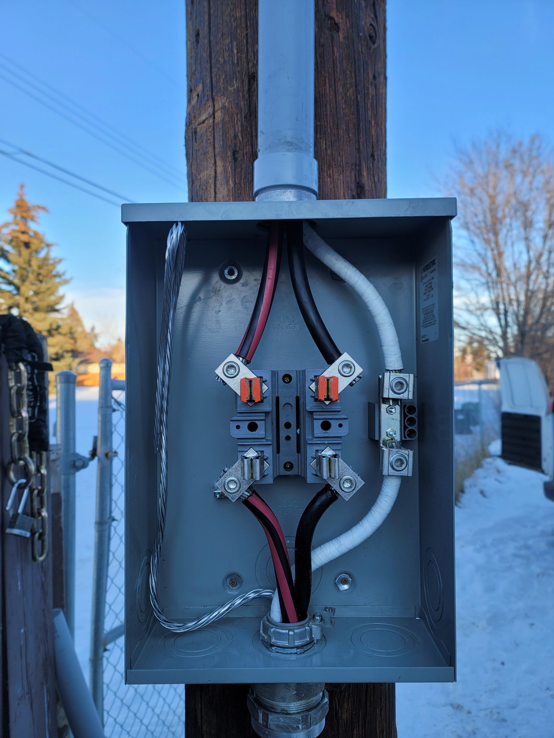 Electrical junction box mounted on a wooden utility pole with wires and connections visible.