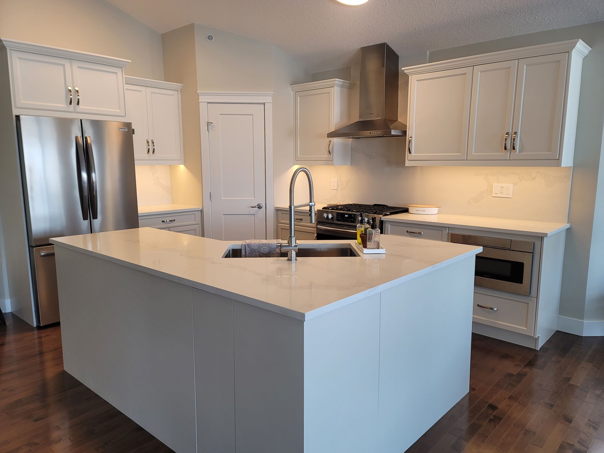 A kitchen with white cabinets , stainless steel appliances , and a large island.