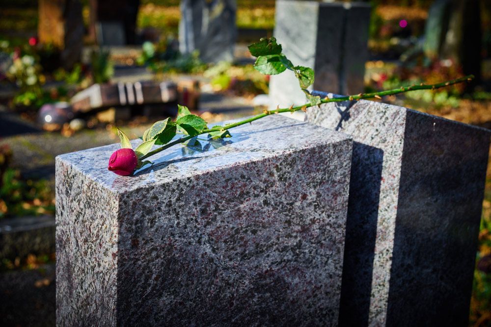 Red Rose Is Sitting On Top Of A Gravestone In A Cemetery — Northern Rivers Headstones in Mullumbimby, NSW