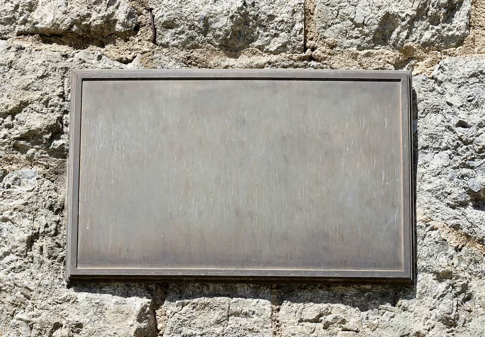 Metal Sign Is Hanging On A Stone Wall — Northern Rivers Headstones in Casino, NSW