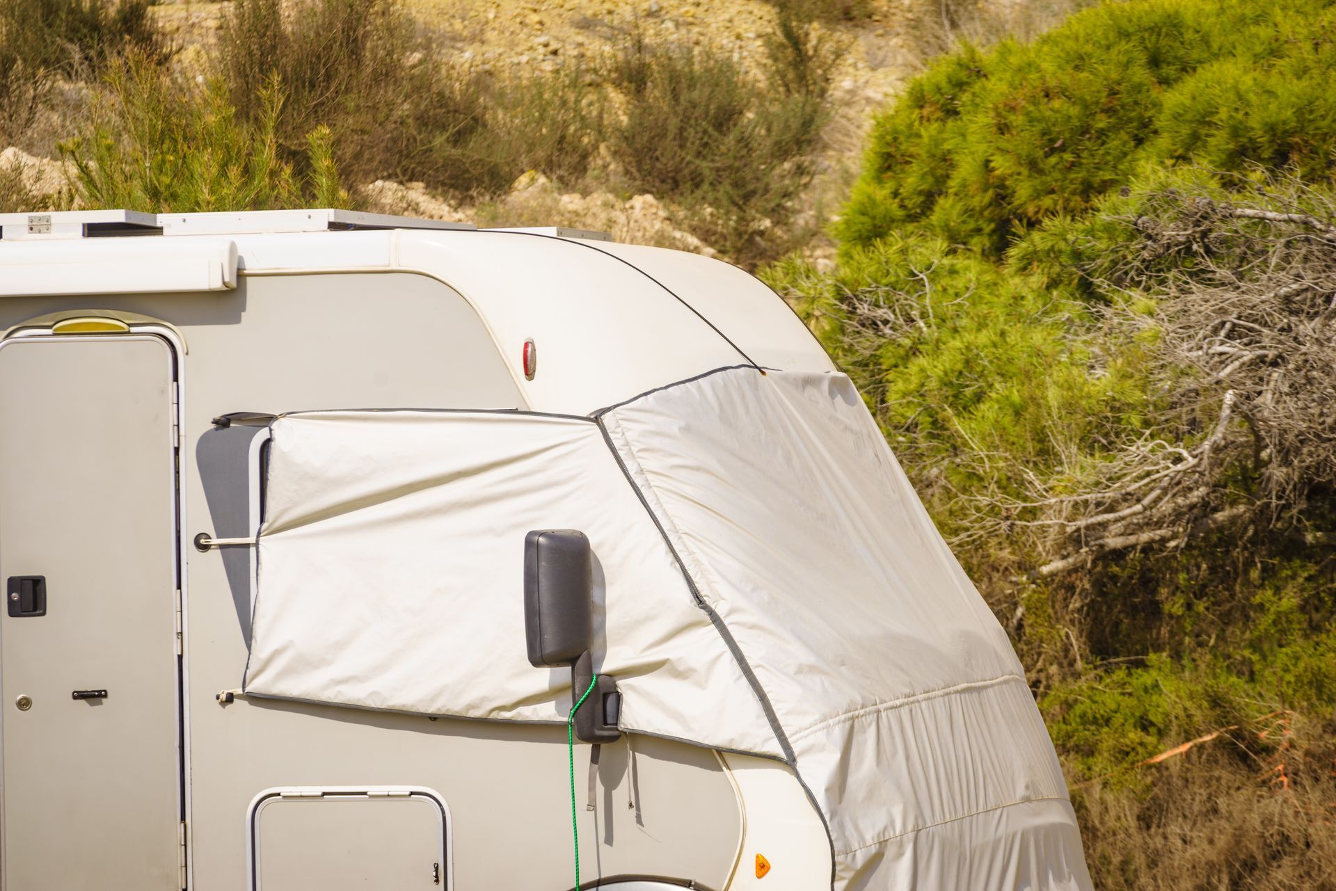 RV camper with exterior accessories and cover at an outdoor campsite location RV camper with exterior accessories and cover at an outdoor campsite location