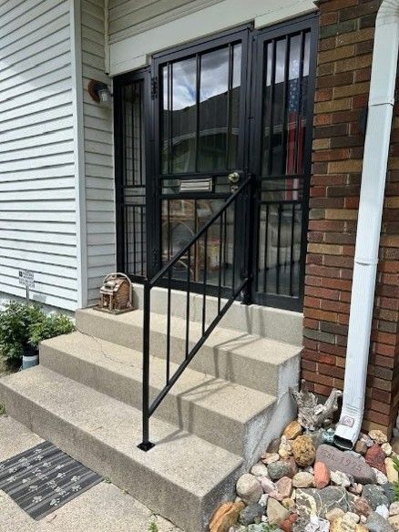 Custom steel exterior railing installed on residential front entry steps by a local railing contractor