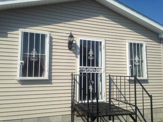 Residential home with custom steel security doors and matching window security bars installed on the exterior