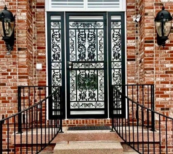 Custom ornamental steel security door installed on a brick residential home entrance with matching exterior railings Custom ornamental steel security door installed on a brick residential home entrance with matching exterior railings
