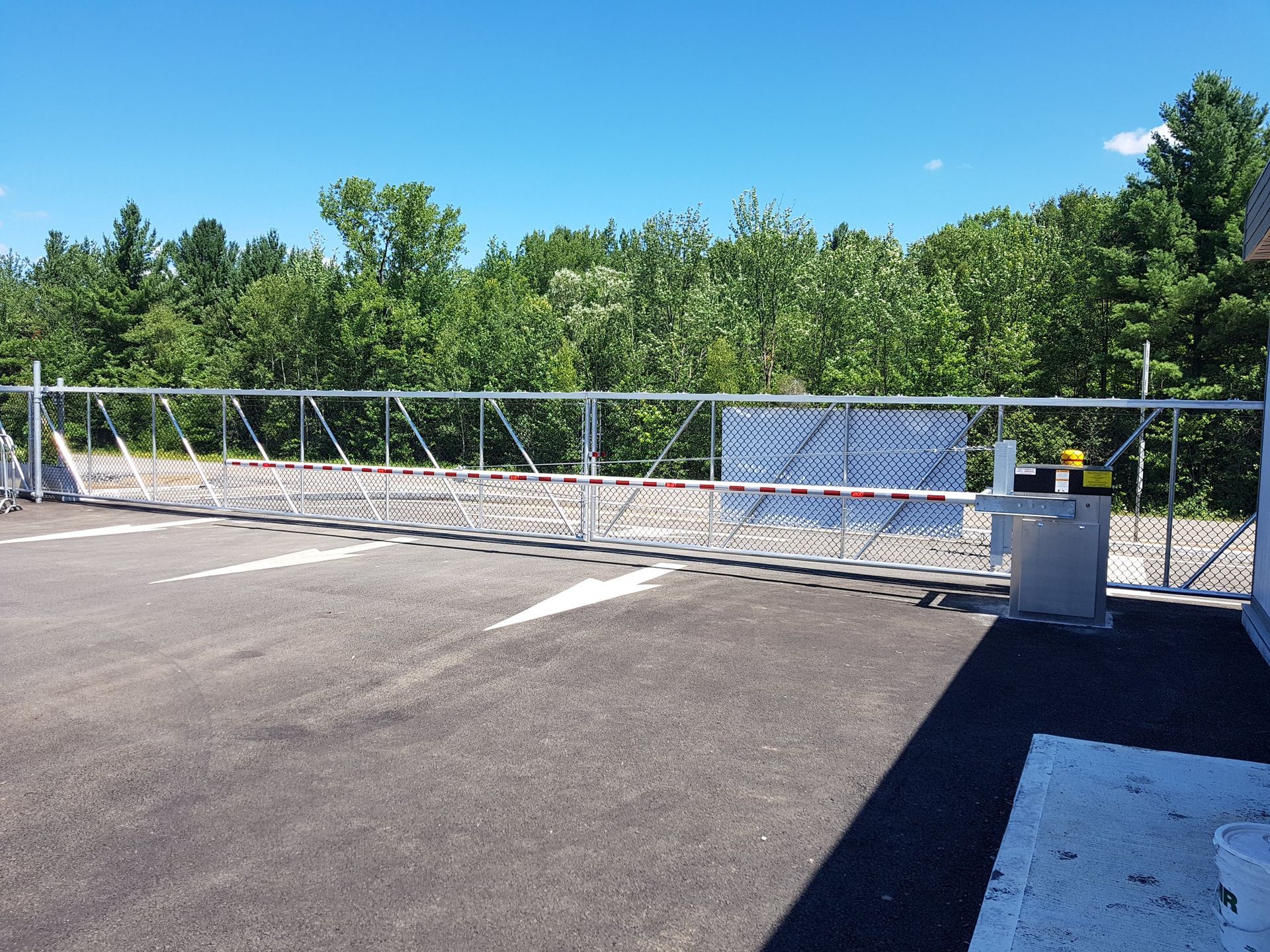 Un parking avec une clôture et des arbres en arrière-plan.
