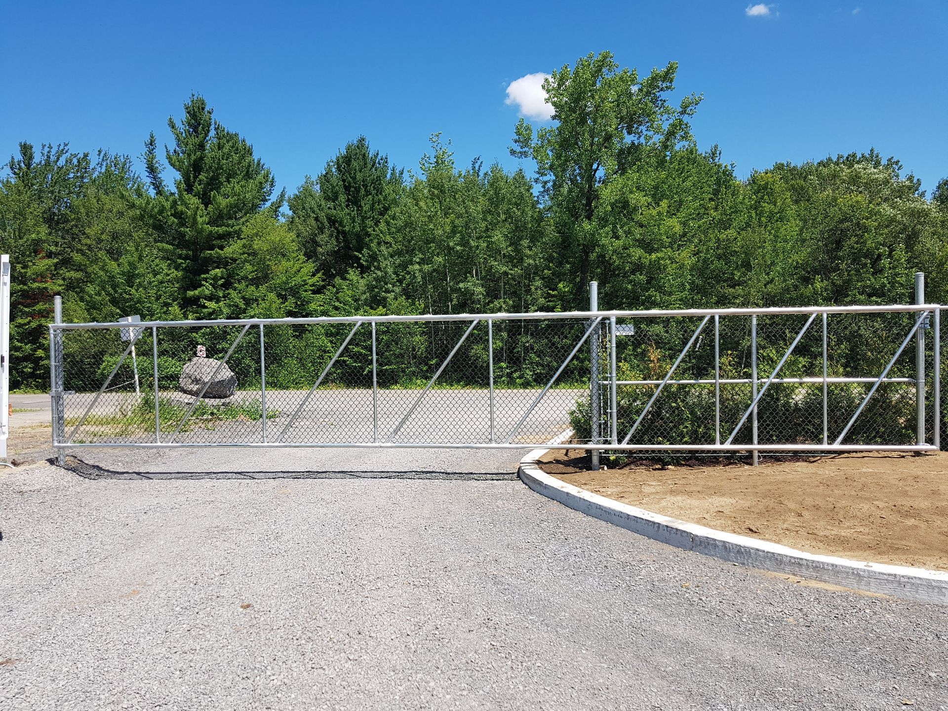 Une porte en métal se trouve au milieu d'un chemin de gravier.