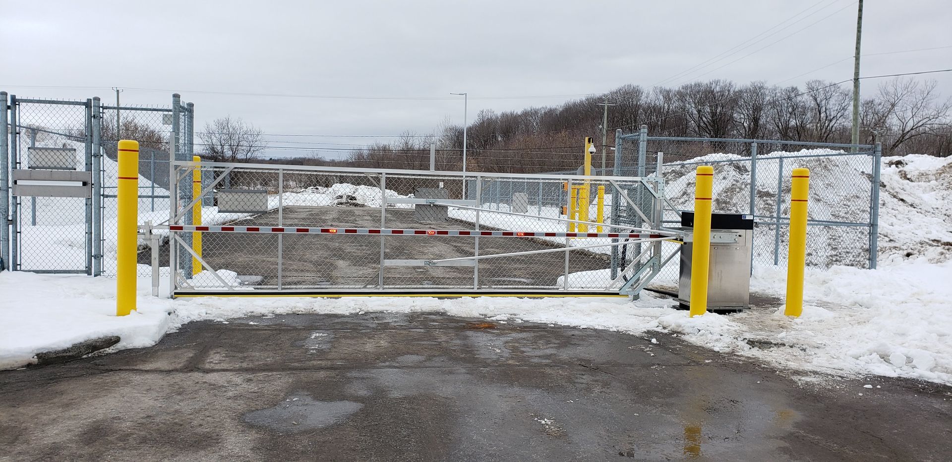 Un parking enneigé avec une clôture et un portail.