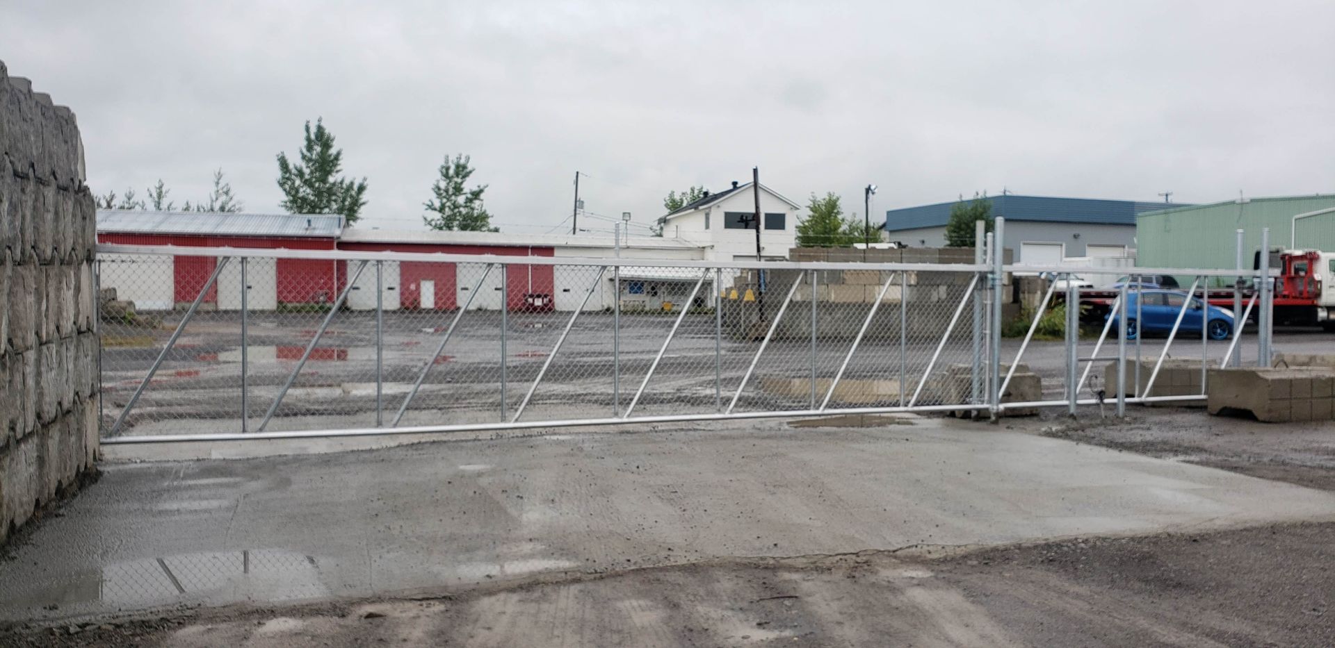 Un portail coulissant dans un parking avec un bâtiment en arrière-plan