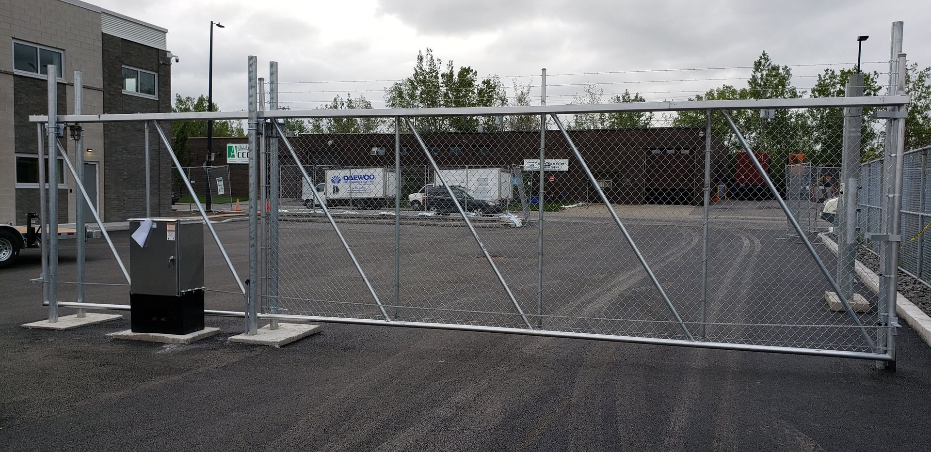 Une clôture grillagée avec un portail au milieu d'un parking