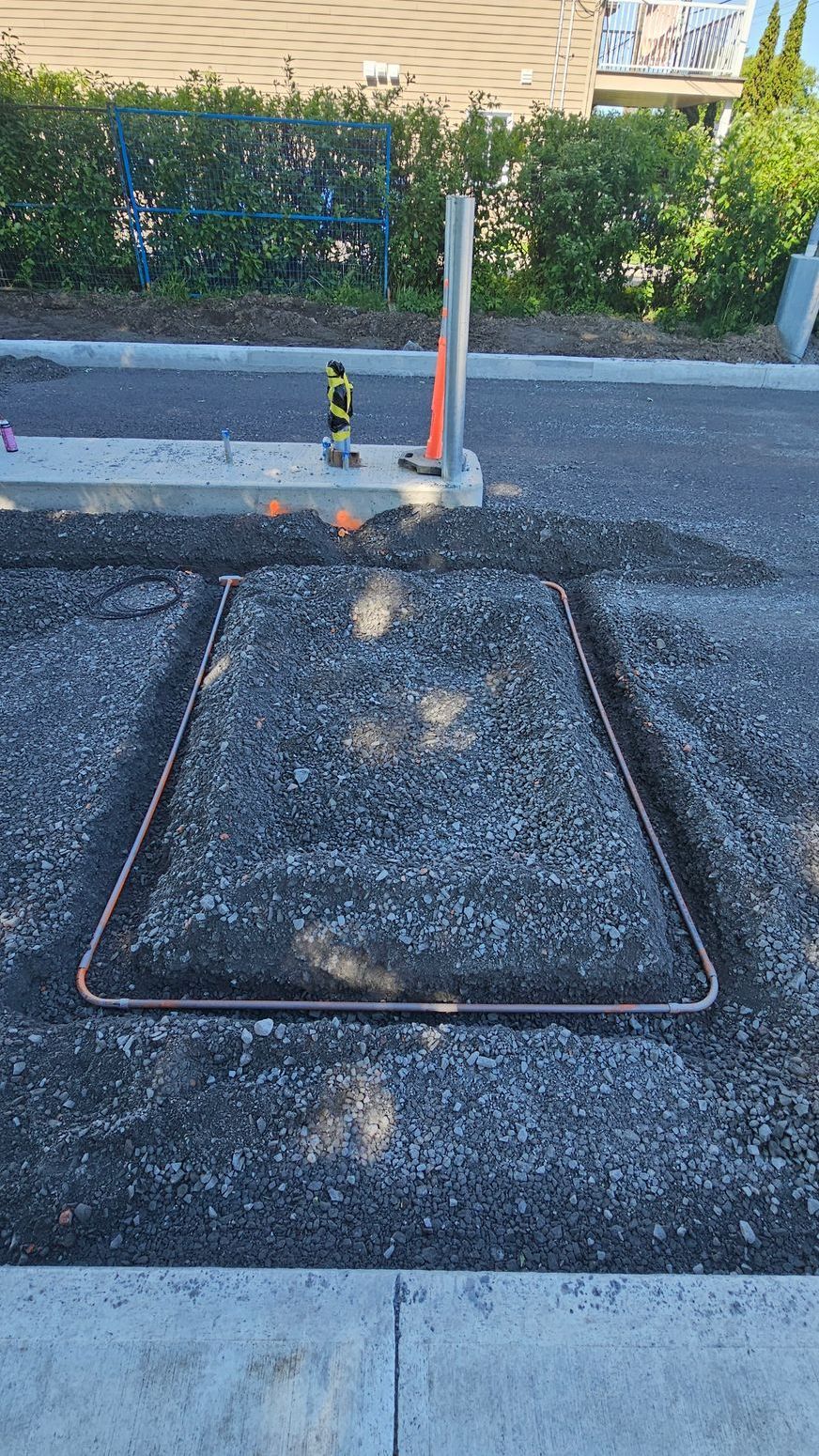 Un fil de cuivre est en train d'être installé dans le sol d'un parking.