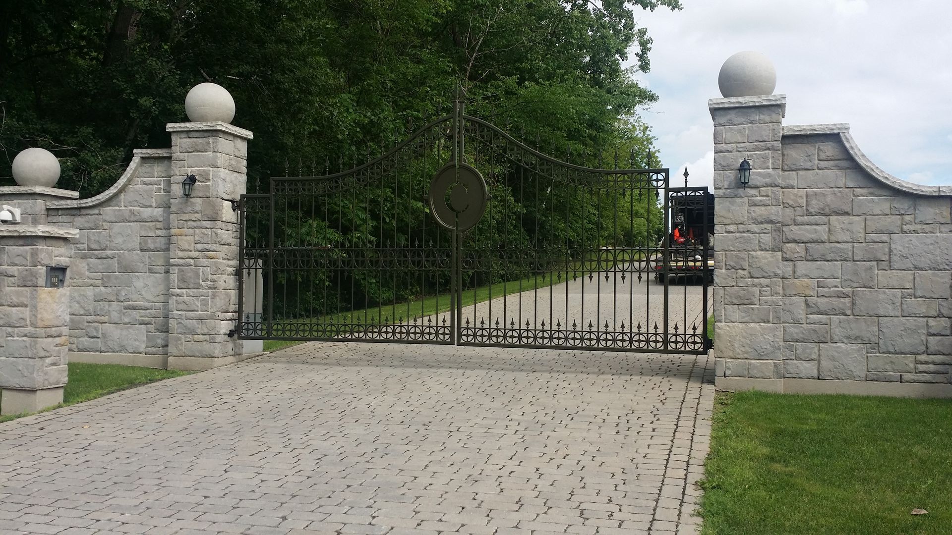 Une allée avec un mur de pierre et un portail en métal